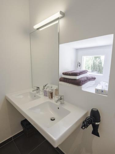 a white bathroom with a sink and a mirror at La Moutière in Colonzelle
