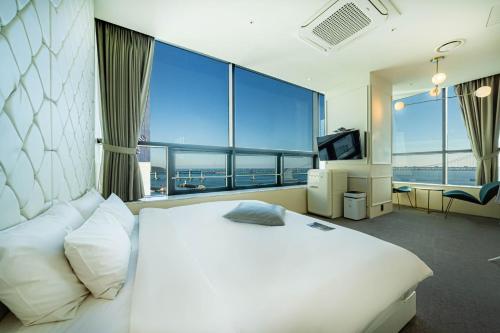 a bedroom with a large white bed and a large window at H Avenue Hotel Gwangalli branch in Busan