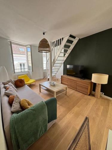 a living room with a couch and a tv at Le Duplex Du Château in Fontainebleau