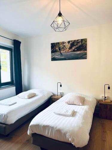 two twin beds in a room with two lamps at Le Coffee Ride Cycling Cafe in Stavelot