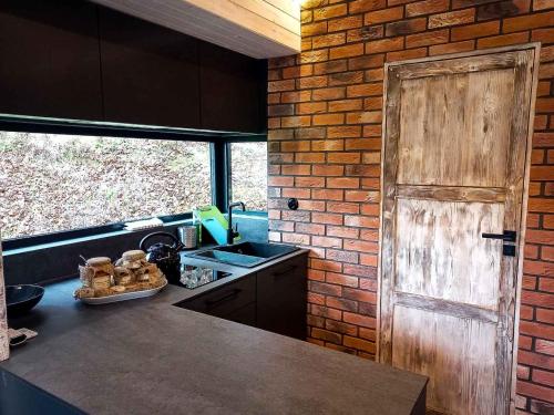 a kitchen with a sink and a brick wall at Rózin 1850 Pstragarnia Czas płynie wolniej. Dubie. in Krzeszowice