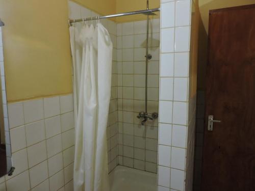 La salle de bains est pourvue d'une douche avec un rideau de douche blanc. dans l'établissement KLH REST HOUSE, à Karatu