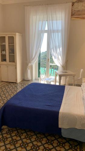 a bedroom with a large blue bed and a window at villa verde sul mare in Vietri sul Mare