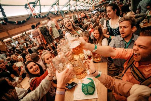 un gruppo di persone che regge bicchieri di birra di ESN Oktoberfest Campsite a Monaco
