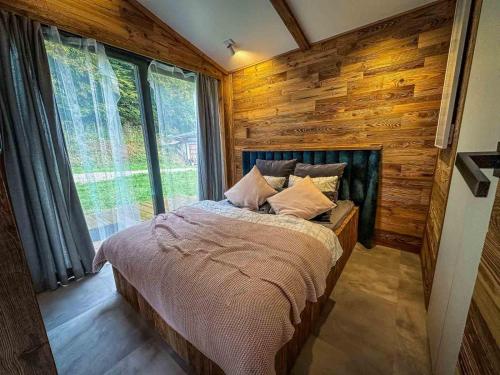 ein Schlafzimmer mit einem Bett in einem Zimmer mit Holzwänden in der Unterkunft Rózin 1850 Pstragarnia Czas płynie wolniej. Dubie. in Krzeszowice