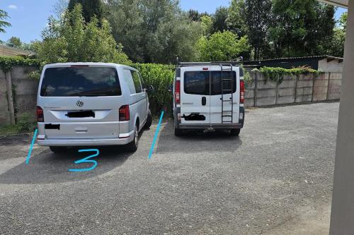 2 camionnettes blanches garées sur un parking dans l'établissement Studio avec jardin et parking 03, à Villenave-dʼOrnon