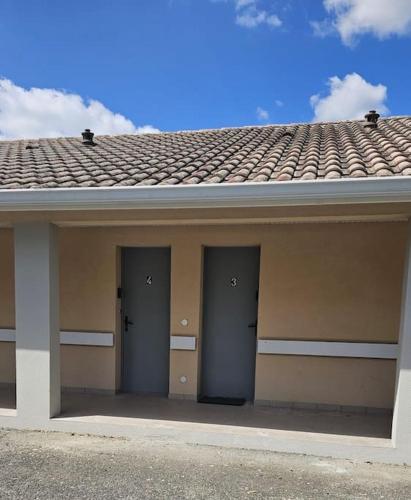 un bâtiment avec trois portes et un toit dans l'établissement Studio avec jardin et parking 03, à Villenave-dʼOrnon