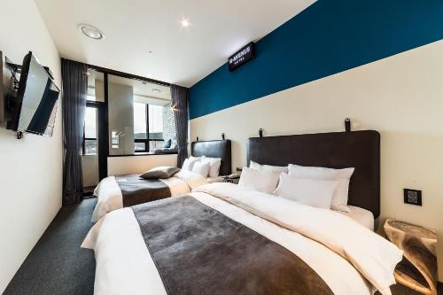 a bedroom with two beds and a blue wall at H Avenue Hotel Gwangalli branch in Busan