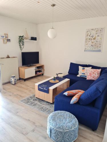 a living room with a blue couch and a tv at Ferienhaus Weitblick in Busenwurth
