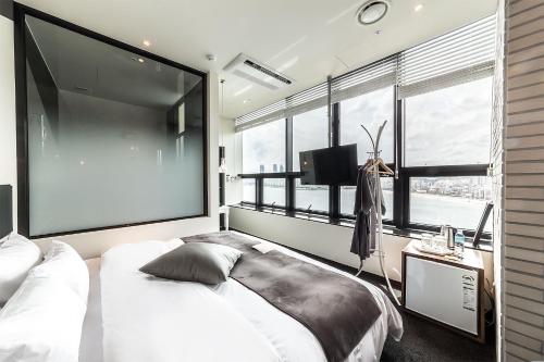 a bedroom with a large white bed and a large window at H Avenue Hotel Gwangalli branch in Busan