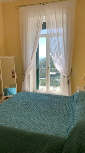 a bedroom with a bed and a large window at villa verde sul mare in Vietri sul Mare