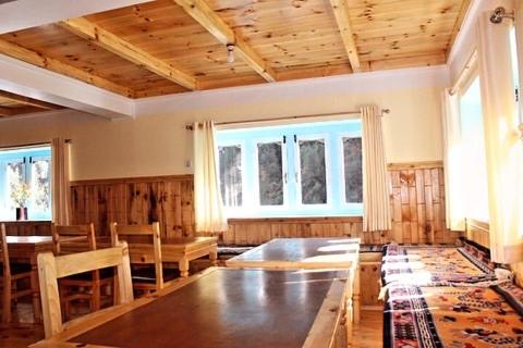 a dining room with a large wooden table and chairs at Hotel waterfall,Benkar in Phakding