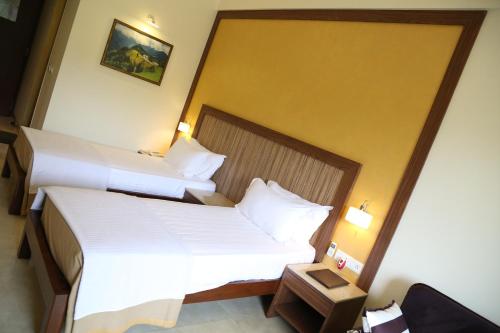 two beds in a hotel room with white sheets at VITS Lonavala in Lonavala