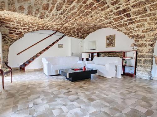 Elle comprend un salon doté d'un mobilier blanc et d'un mur en pierre. dans l'établissement Authenticité, jardin, terrasse et vue, à Chanac