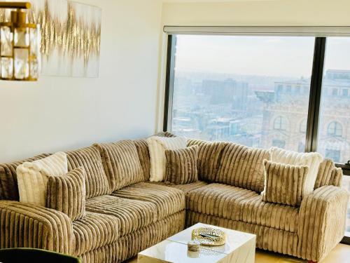 un sofá en una sala de estar con una gran ventana en Relax On The Penthouse Floor DTLA With A View en Los Ángeles