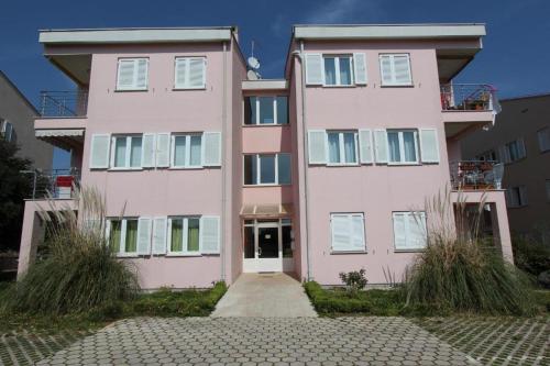 um edifício de apartamentos cor-de-rosa com uma entrada em frente em Apartments Lola em Rovinj