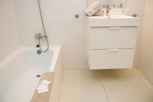 a white bathroom with a sink and a bath tub at Capitain Beachside Haven in Acantilado de los Gigantes