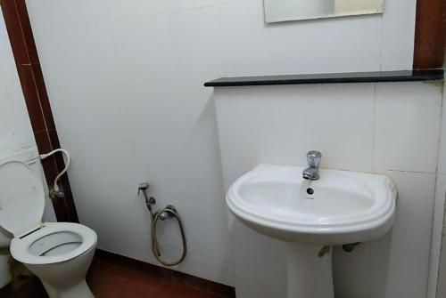 La salle de bains blanche est pourvue de toilettes et d'un lavabo. dans l'établissement Hotel Mira international - Luxury Stay - Best Hotel in digha, à Digha