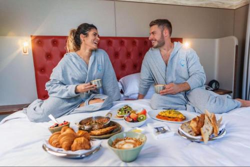un homme et une femme assis sur un lit avec de la nourriture dans l'établissement Hyatt Centric Jumeirah - Dubai Twin Room - UAE, à Dubaï