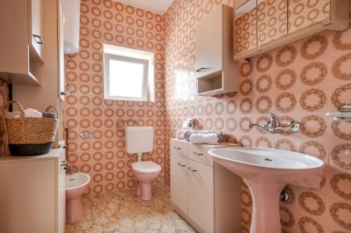 un bagno rosa con lavandino e servizi igienici di Rooms Goreta a Kaštela (Castelli)