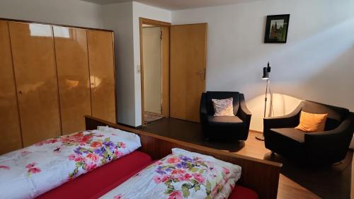 een slaapkamer met een bed, 2 stoelen en een spiegel bij Ruhige Oase in traumhafter Lage in Rabennest