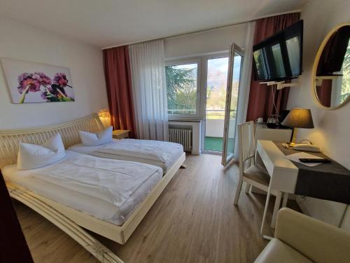 a bedroom with a bed and a desk and a television at Apart Hotel Freiburg in Freiburg im Breisgau