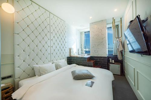 a bedroom with a white bed and a television at H Avenue Hotel Gwangalli branch in Busan