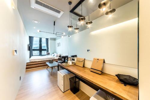 a room with a desk and a couch in the background at H Avenue Hotel Gwangalli branch in Busan