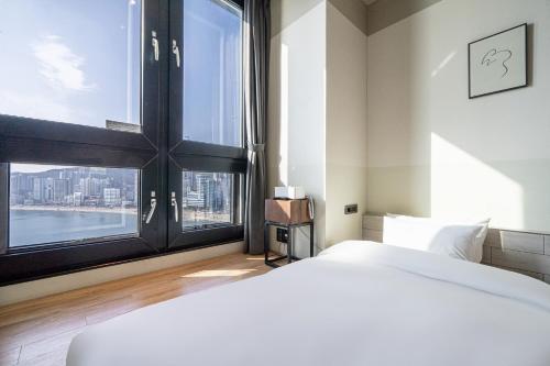 a bedroom with a large bed and a large window at H Avenue Hotel Gwangalli branch in Busan