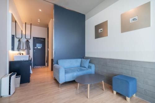 a living room with a blue chair and a table at H Avenue Hotel Gwangalli branch in Busan