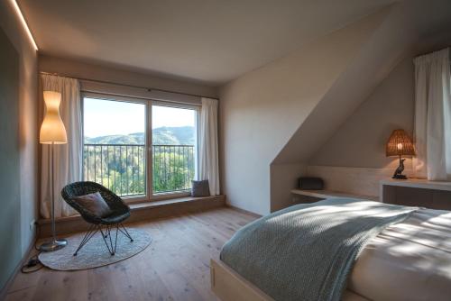 um quarto com uma cama, uma cadeira e uma janela em Traumhaftes Ferienhaus am Lateinberg - 8455 Eibiswald Südsteiermark em Eibiswald
