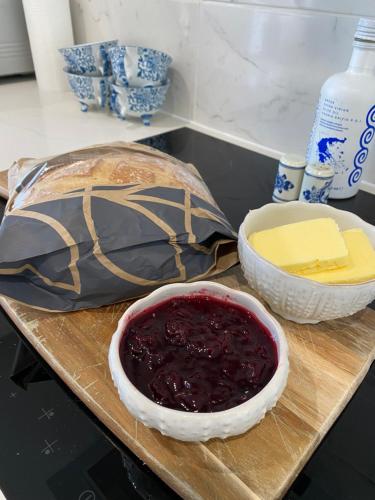 a cutting board with a bowl of jam and a bowl of cheese at The Pelican Room-converted Cart Lodge near airport in Horsham Saint Faith
