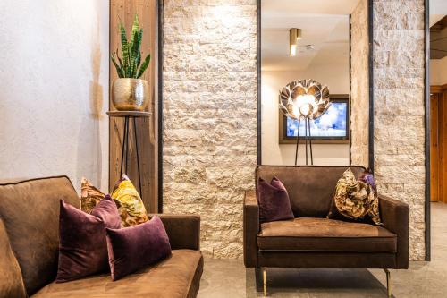 a living room with two brown couches and a mirror at Platzlhof - Mein Hotel im Zillertal in Ried im Zillertal
