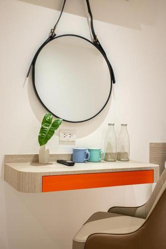 a mirror hanging above a shelf with a chair at L MINITEL at Night Bazaar Chiangmai in Chiang Mai