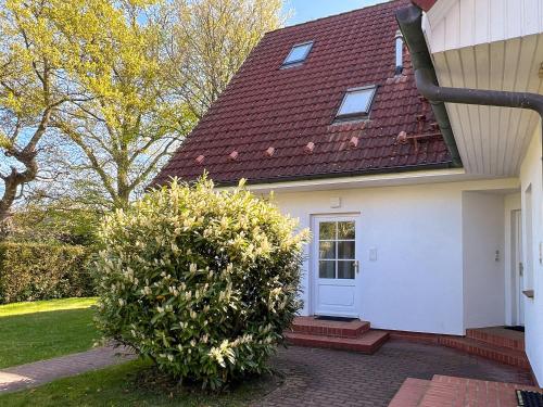 una casa blanca con techo rojo y dos arbustos en Kormoran 19, en Zingst