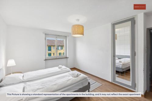 Cette chambre blanche comprend un lit et un miroir. dans l'établissement Zurich 2-Bedroom Apartment with Comforts, à Zurich
