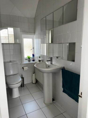 a white bathroom with a sink and a toilet at A gem close to Canford Cliff and Sandbanks beach in Parkstone