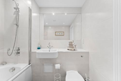 ein weißes Bad mit einem Waschbecken und einem WC in der Unterkunft Tranquil Haven: Serene 2-Bed Retreat in Kent