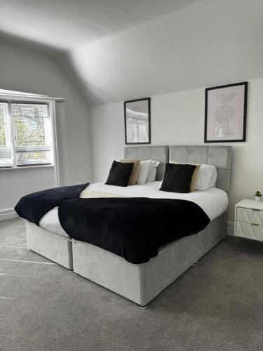een groot bed in een witte kamer met 2 ramen bij A gem close to Canford Cliff and Sandbanks beach in Parkstone