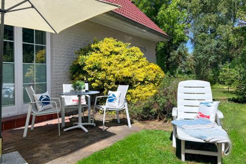 une terrasse avec des chaises, une table et un parasol dans l'établissement Sonnenschein, à Zingst