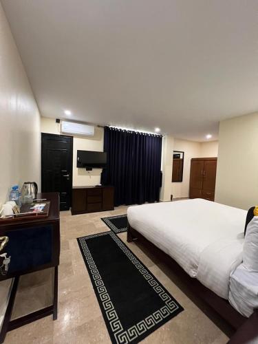 a bedroom with a large white bed and a desk at BULAND HEIGHTS in Murree