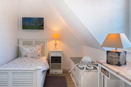 een kleine slaapkamer met een bed en een tafel met een lamp bij Strandhaus Zingst in Zingst
