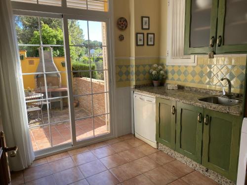 a kitchen with a sink and a sliding glass door at Casa la Querencia del Lago Alojamiento Rural in Las Jaras