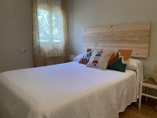 a bedroom with a white bed with two pillows at Casa la Querencia del Lago Alojamiento Rural in Las Jaras