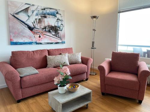 a living room with a pink couch and two chairs at Irma 28, Sandwall in Wyk auf Föhr