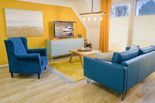 ein Wohnzimmer mit 2 blauen Stühlen und einem Tisch in der Unterkunft Tordalk, Whg 06 in Prerow