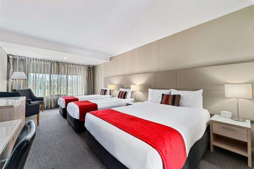 a hotel room with two beds and a chair at Quality Hotel Parklake Shepparton in Shepparton