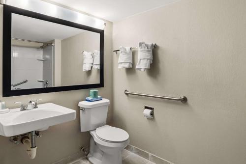 a bathroom with a toilet and a sink and a mirror at Suburban Studios Columbia Northwest in Columbia