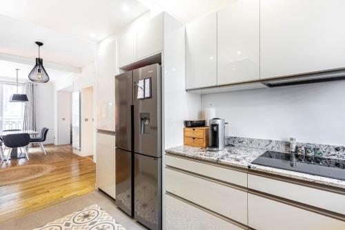 une cuisine avec des armoires blanches et un réfrigérateur noir dans l'établissement GuestReady - Espace lumineux à Neuilly-sur-Seine, à Neuilly-sur-Seine