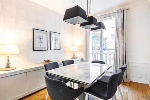 une salle à manger avec une table et des chaises en verre dans l'établissement GuestReady - Espace lumineux à Neuilly-sur-Seine, à Neuilly-sur-Seine